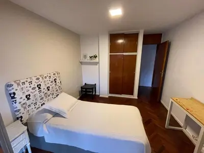 a bedroom with a white bed and a wooden floor at Depto Nva Cba mts Parque Sarmiento in Cordoba
