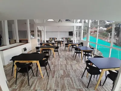 a restaurant with tables and chairs and a pool at HOTEL CRISTAL in Villa Carlos Paz