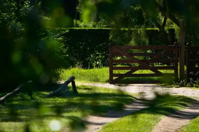 a wooden gate in the grass next to a field at La Argentina Complejo in Villa Ciudad de America