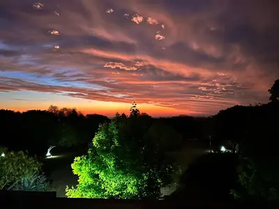 a sunset in the sky with trees in the foreground at Pueblo Santo, Cabañas & Suites in San Javier