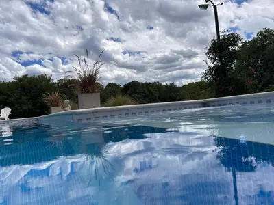 a large swimming pool with a cloudy sky in the background at Pueblo Santo, Cabañas & Suites in San Javier