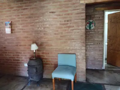 a blue chair next to a brick wall with a wood stove at Al pie del cerro in San Javier
