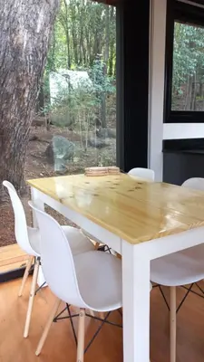 a wooden table and white chairs in a room with a tree at Casa Container Embalsina Villa del Dique in Villa del Dique