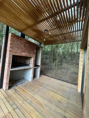 a patio with a brick fireplace and a wooden deck at Casa Container Embalsina Villa del Dique in Villa del Dique