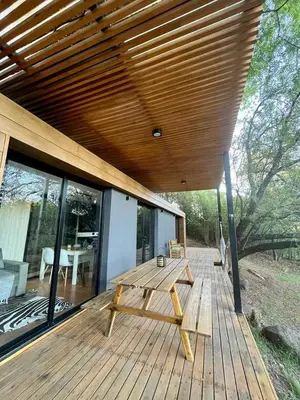a wooden deck with a picnic table under a roof at Casa Container Embalsina Villa del Dique in Villa del Dique