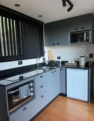 a kitchen with gray cabinets and a white counter top at Casa Container Embalsina Villa del Dique in Villa del Dique
