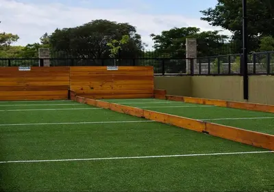 a tennis court with green grass and wooden walls at Veneto Village - Vista al Lago - 10 minutos a Carlos Paz in Villa Parque Siquiman