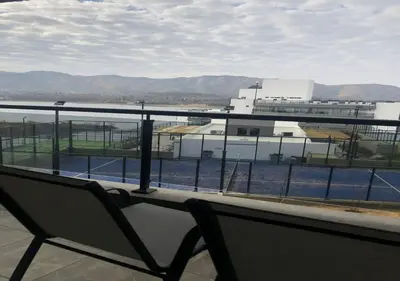 a chair sitting on a balcony with a tennis court at Veneto Village - Vista al Lago - 10 minutos a Carlos Paz in Villa Parque Siquiman