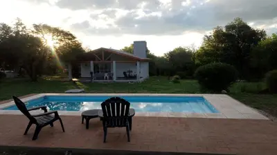 two chairs and a table next to a swimming pool at Cabaña de Emma in Villa de Las Rosas