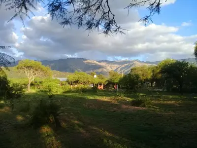 a field with trees and mountains in the background at Cabaña de Emma in Villa de Las Rosas