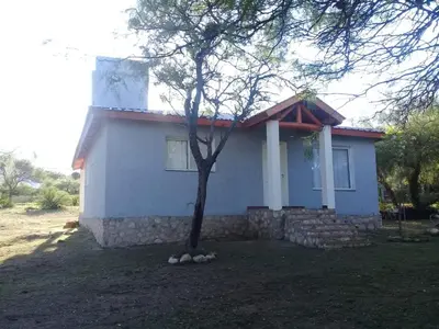 a small white house with a tree in front of it at Cabaña de Emma in Villa de Las Rosas