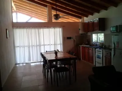 a kitchen with a table and chairs and a kitchen with a window at Cabaña de Emma in Villa de Las Rosas