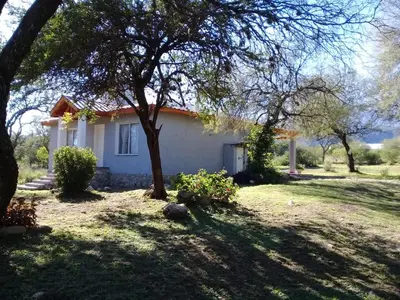 a white house with a tree in the yard at Cabaña de Emma in Villa de Las Rosas