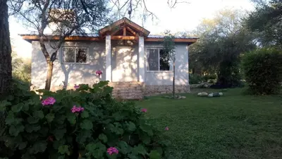 a small house in a yard with flowers at Cabaña de Emma in Villa de Las Rosas