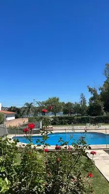 a swimming pool with red flowers in front of it at Depto del Lago in Villa Carlos Paz