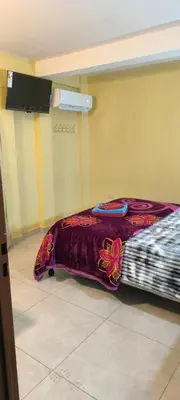 a bed in a room with a purple blanket at Departamentos Los Almendros in Merlo