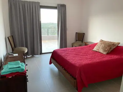 a bedroom with a red bed and a large window at Casal Sur in Potrero de Garay
