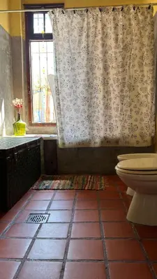 a bathroom with a toilet and a shower curtain at Hostel del pueblo in Amboy