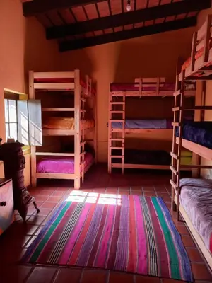 a room with several bunk beds and a rug at Hostel del pueblo in Amboy