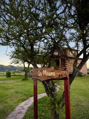 a sign in front of a tree with a house at Cabaña La Maura in La Estancia