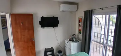 a room with a television on a wall with a refrigerator at Tempo Suites in Cordoba