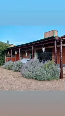 a building with purple plants in front of it at Cabaña Los Espinillos in Cortaderas