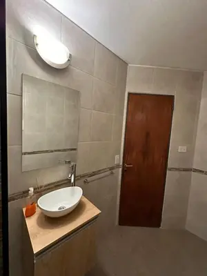 a bathroom with a sink and a mirror and a door at Paseo del Boulevard Suite in Cordoba