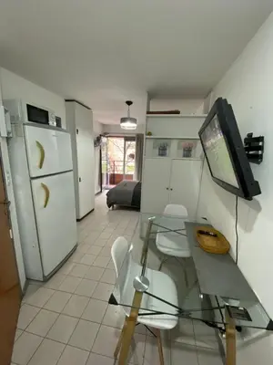a kitchen with a table and a tv on a wall at Monoambiente en Nueva Córdoba in Cordoba