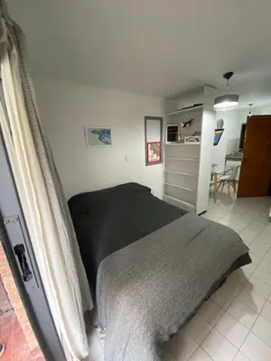 a bedroom with a black bed and a kitchen at Monoambiente en Nueva Córdoba in Cordoba
