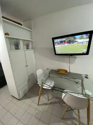 a room with a glass table and a television on a wall at Monoambiente en Nueva Córdoba in Cordoba