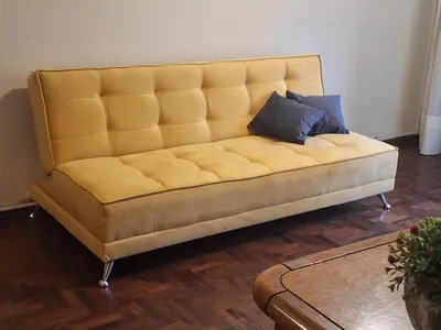 a yellow couch with two pillows on it in a room at cordoba departamentos por dia cañada in Cordoba