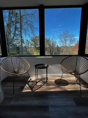 two chairs and a stool in front of a window at Casa Raíz Cumbrecita in La Cumbrecita
