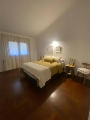 a bedroom with a bed and a table and a window at Casa Raíz Cumbrecita in La Cumbrecita