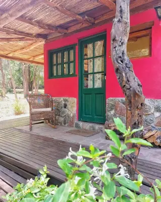 a red house with a green door and a bench on a deck at Cabañas spa el petrel in San Javier
