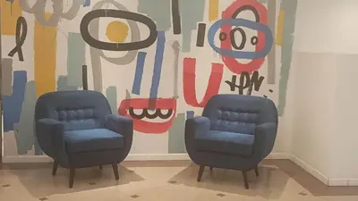 two blue chairs in front of a wall with a painting at Departamento 3 Paris - Edificio VILAUT by INMOVE Temporarios in Cordoba