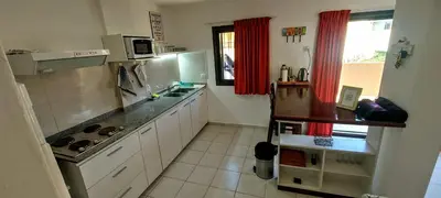 a kitchen with white cabinets and red curtains at Oasis depto en centro carlos paz in Villa Carlos Paz