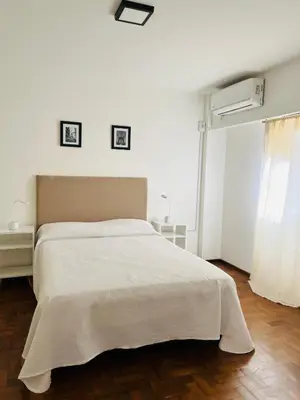 a white bedroom with a large bed and a window at Departamento confortable centro Wi Fi - cochera opcional in Cordoba