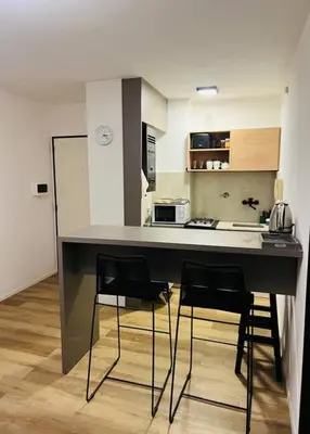 a kitchen with a counter with four chairs around it at Departamento confortable centro Wi Fi - cochera opcional in Cordoba
