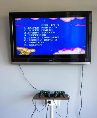 a television on a wall with two controllers on a table at Nuevo Hotel Carmel in Villa Carlos Paz