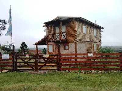 a wooden house on a fence in a field at Cabaña La Fortaleza Villa Yacanto in Villa Yacanto