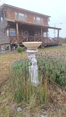 a bird bath in front of a log house at Cabaña La Fortaleza Villa Yacanto in Villa Yacanto