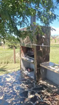 a stone oven in a field with a tree at Cabaña La Fortaleza Villa Yacanto in Villa Yacanto
