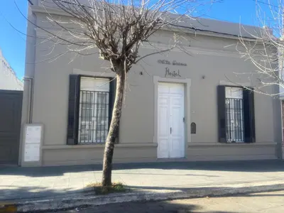 a tree in front of a white building at Alta Gracia Hostel in Alta Gracia