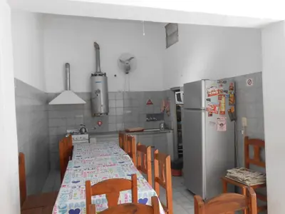 a kitchen with a table and chairs and a refrigerator at Alta Gracia Hostel in Alta Gracia