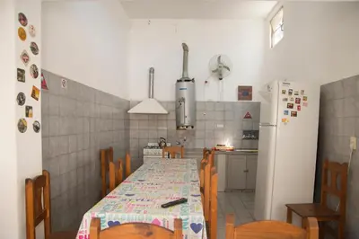 a kitchen with a table with chairs and a refrigerator at Alta Gracia Hostel in Alta Gracia