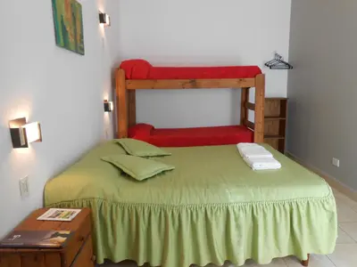 a small bedroom with a green bed with a red bench at Alta Gracia Hostel in Alta Gracia