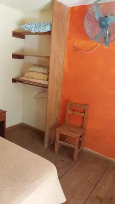 a room with a bed and a chair and a fan at Cabañas walcarpi in Villa Ciudad Parque
