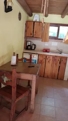 a kitchen with a wooden table and wooden cabinets at Cabañas walcarpi in Villa Ciudad Parque
