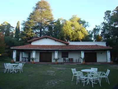a white house with tables and chairs in the yard at Cabañas La Victoria, Las Calles, Traslasierras, Córdoba in Las Rabonas