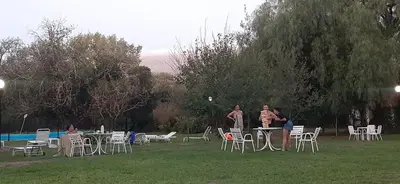two people standing in a field with tables and chairs at Cabañas La Victoria, Las Calles, Traslasierras, Córdoba in Las Rabonas